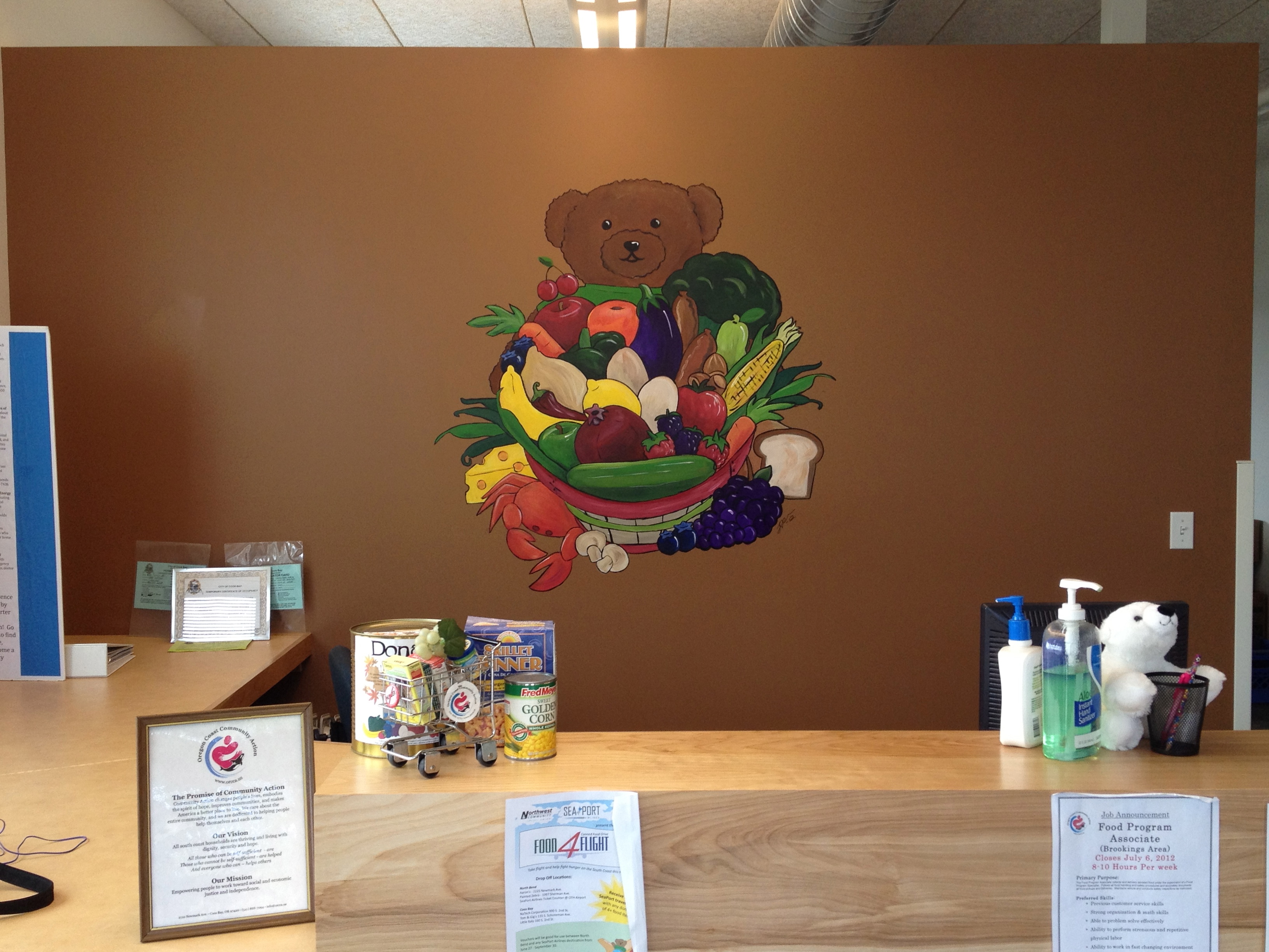 Joshann painting mural of a bear holding a basket of fruits and vegetables 2