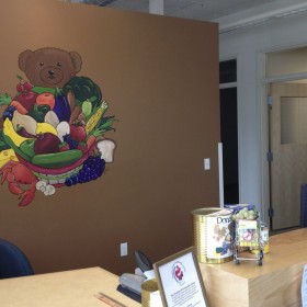 Joshann painting mural of a bear holding a basket of fruits and vegetables 1